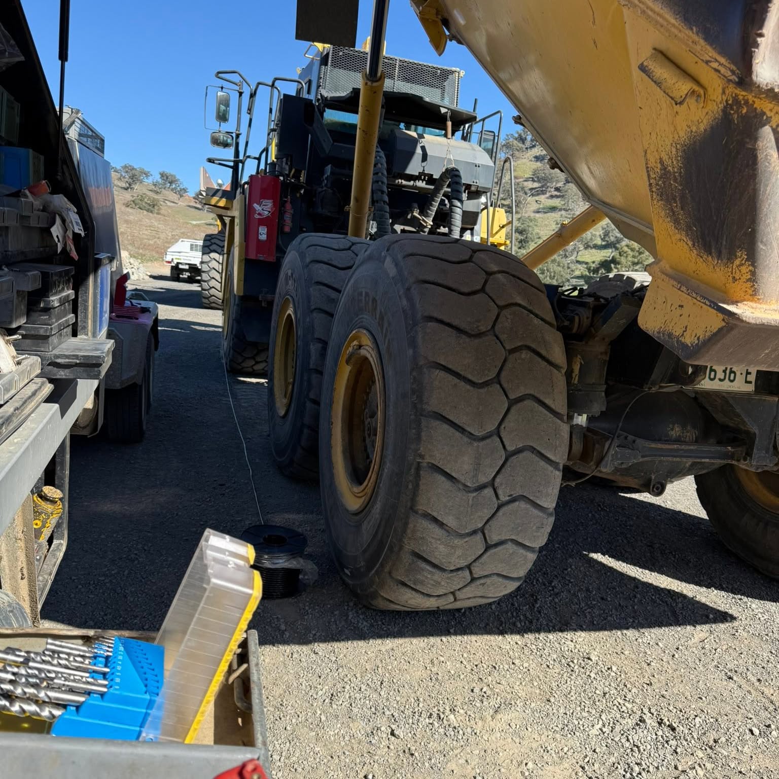 Auto electrical work underway on a large earthmover wheel, tools laid out on a mat beside it